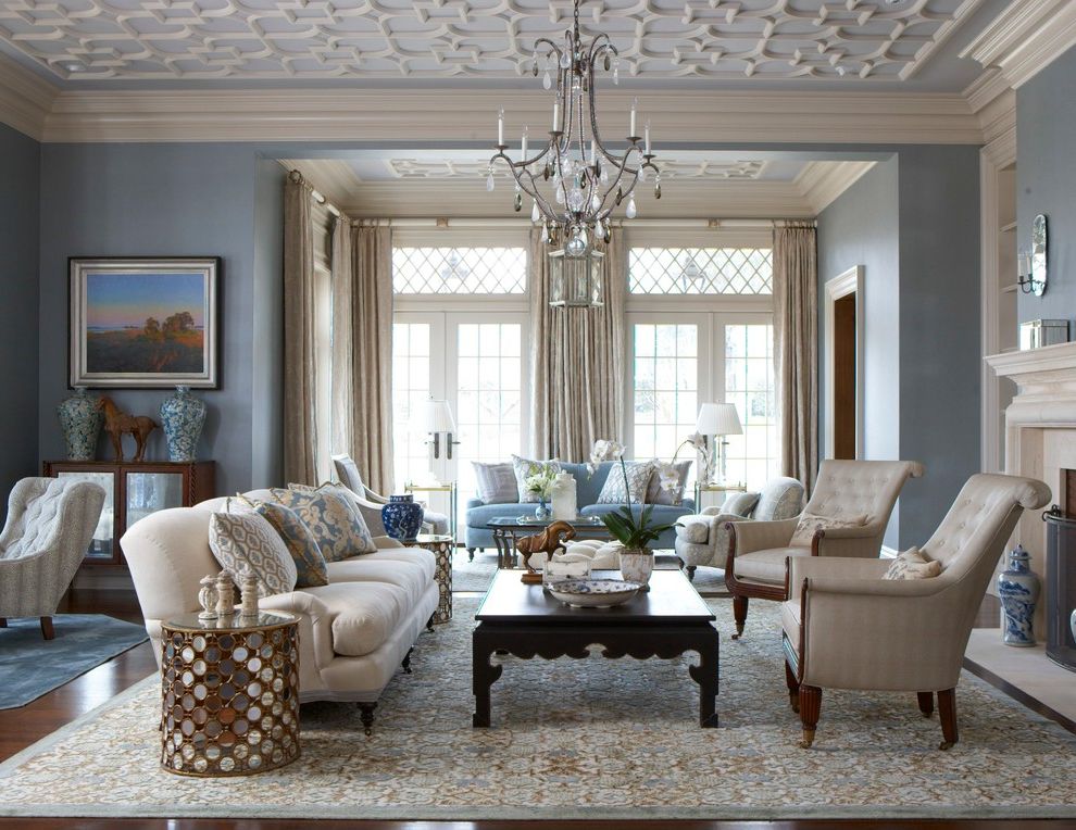 Blue and Tan Area Rugs with Traditional Living Room  and Area Rug Blue Color Scheme Blue Walls Ceiling Pattern Cream Curtains Cream Sofa Crown Molding Crystal Chandelier Decorative Pillows Fireplace Screen Mirror End Table Multiple Seating Areas