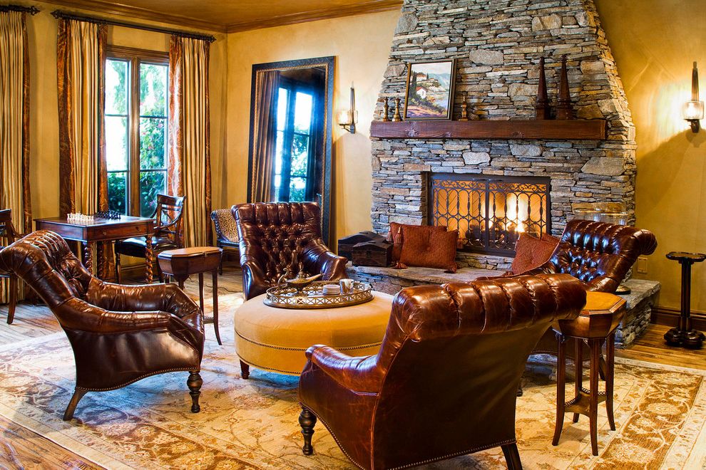 Distressed Leather Club Chair with Mediterranean Living Room  and French Doors Gold Rug Hurricane Sconce Leather Club Chair Long Drapes Round Ottoman Stone Fireplace Tray Tufted Leather Chair Tuscan Wood Mantel Wood Trim