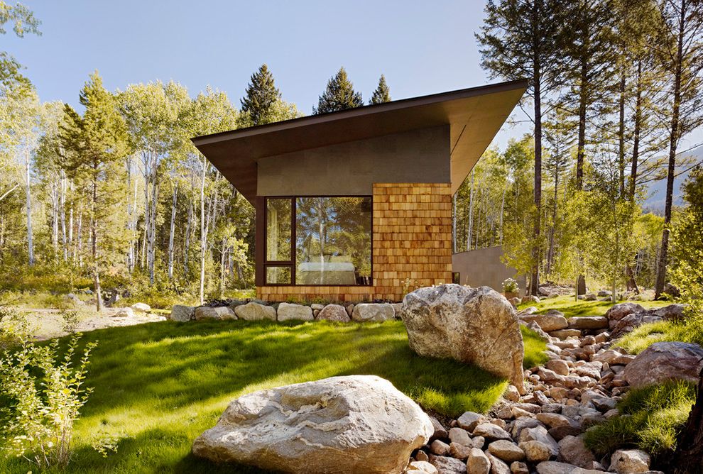 Estes Roofing with Contemporary Exterior and Boulders Butterfly Roof Cladding Corner Window Dry Creek Glass Windows Grass Large Windows Metal Roof Modern Rustic Overhang Patio Pine Trees Shingles Stone Path