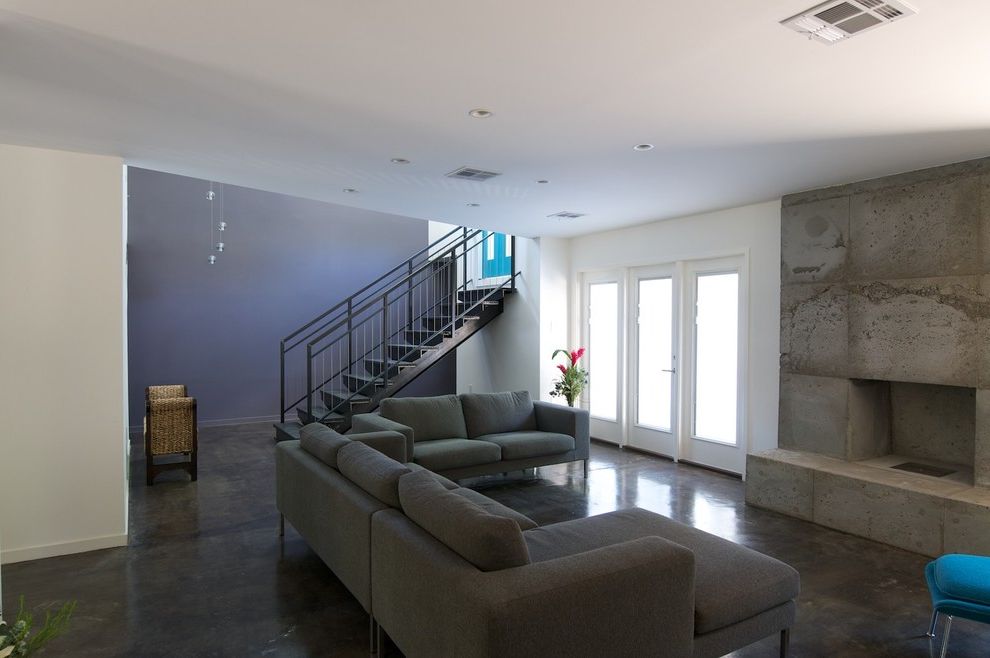 Poured Concrete Floors with Contemporary Living Room  and Blue Accent Wall Blue Chair Concrete Fire Surround Glass Patio Doors Metal Staircase Open Staircase Pendant Lamp Polished Concrete Sectional