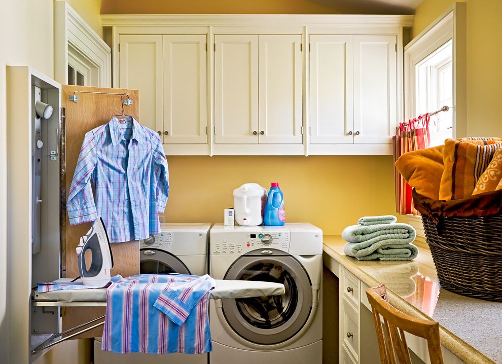 Room and Board Sale with Traditional Laundry Room  and Built in Storage Fold Out Ironing Board Front Loading Washer and Dryer Gold Walls Ironing Boards Shaker Style Wall Ironing Board White Cabinets Wicker Basket Wood Cabinets