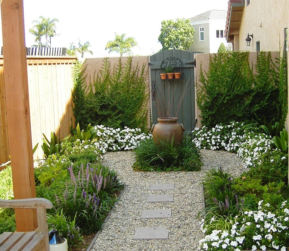 Serenity Rejuvenation Center   Mediterranean Landscape  and Climbing Plants Creeping Fig Decorative Garden Urn Garden Fence Garden Wall Gate Gravel Liriope Mass Plantings Path Pavers Pot Side Yard Small Space Stucco Walls Walkway Wood Fence Wood Fencing