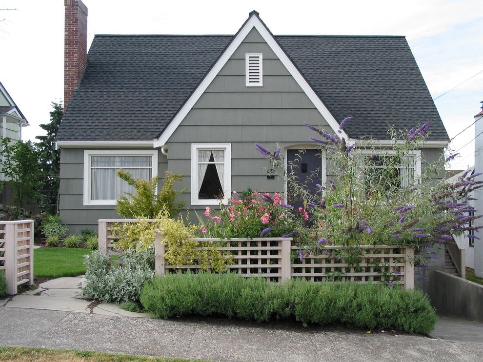 St Pete Housing with Traditional Exterior  and Classic Construction Cross Gabled Roof Dark Gray Door Fence Gray House Gray Siding Gray Walls Pink Flowers Purple Flowers Red Brick Chimney Remodel Seattle Small House Traditional Wood Fence