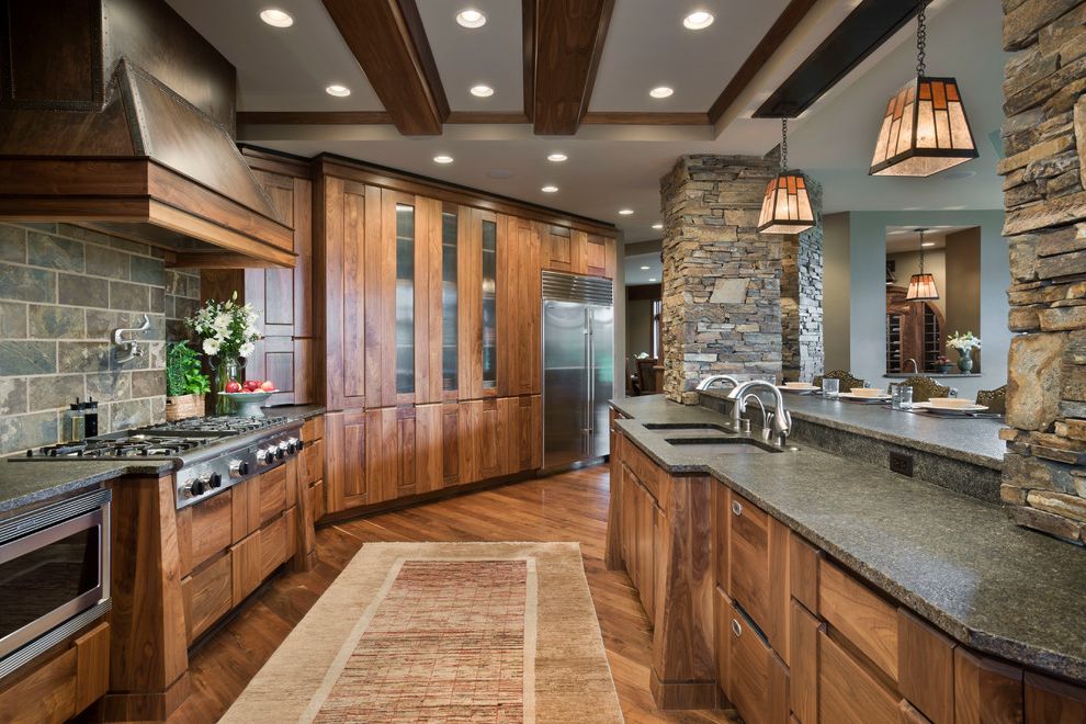 Walnut Ridge Cabinetry   Rustic Kitchen  and Beamed Ceiling Carpet Runner Dark Wood Beams Gray Countertop Pot Filler Recessed Lighting Stained Glass Pendants Stone Columns Stonework Tray Ceiling Wood Hood