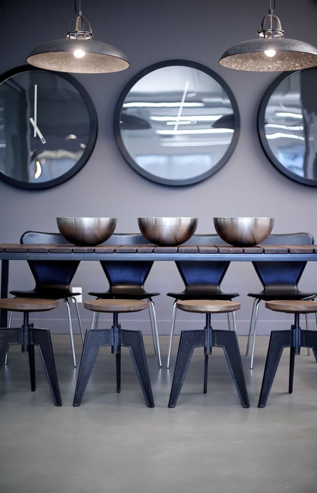 Expanding Circle Table with Modern Dining Room  and Barn Lights Black Chairs Bowls Concrete Floor Dining Stools Gray Walls Round Mirrors Work Space