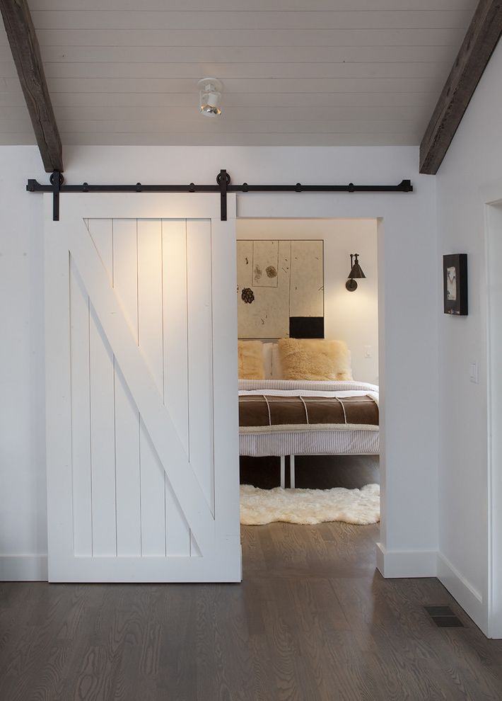 How to Fix a Hole in a Door   Farmhouse Bedroom Also Barn Door Baseboards Ceiling Lighting Dark Floor Exposed Beams Neutral Colors Sliding Doors Wall Art Wall Decor White Wood Wood Ceiling Wood Flooring Wood Trim
