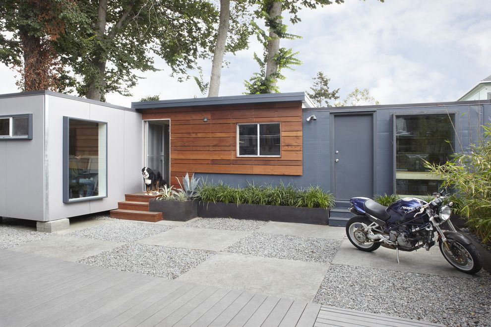 Shipping Container Storage Shed with Contemporary Exterior Also Concrete Patio Concrete Pavers Flat Roof Flowerbeds Gravel Grey Grey Exterior Mixed Materials Modern Exterior Motorcycle One Story Planters Wood Exterior Wood Paneling Wood Stairs